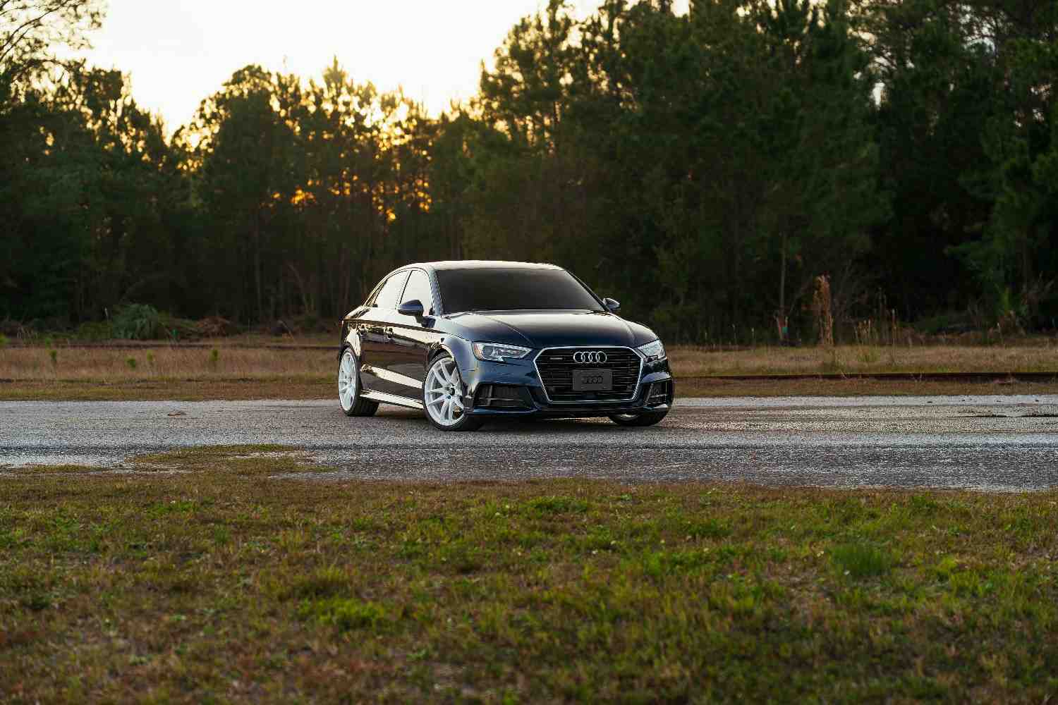 A modern silver sedan driving along a safe coastal highway at sunset, representing security and freedom